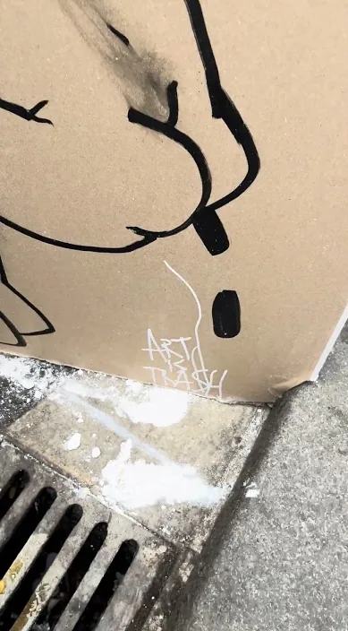 Gezeichneter Karton, der über einem Gullygitter an der Straße lehnt, Barcelona, Art Is Trash
