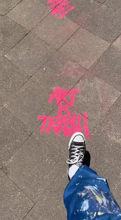 Pinke Sprühschrift „Art Is Trash“ auf dem Gehweg während einer Ausstellung, Düsseldorf